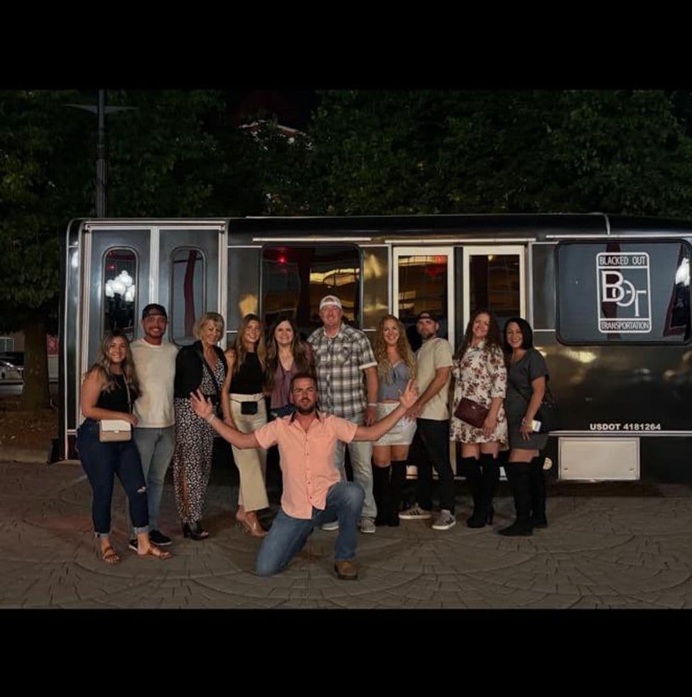 Group of friends posing in front of a food truck at night, smiling and celebrating together.