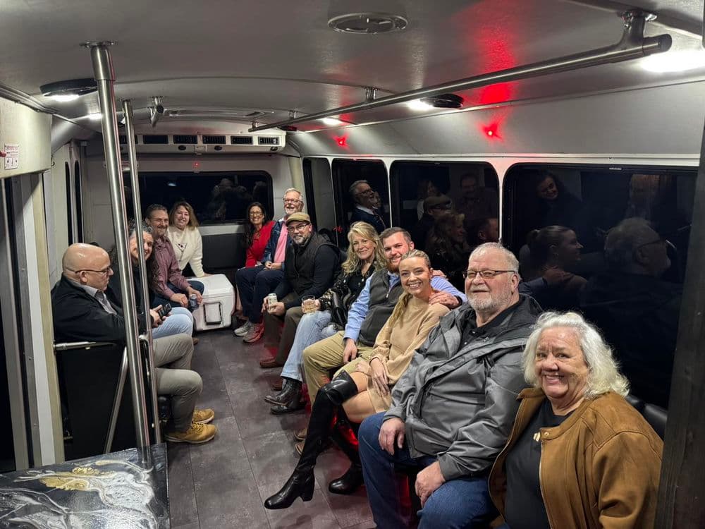Group of diverse people sitting together on a bus, smiling and enjoying each other's company.